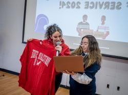 学生玛丽安娜·卢娜-马丁内斯拿着一台电脑，邦纳领导和服务协调员米凯拉·古兹曼拿着一件十大博彩推荐排名运动衫看着.